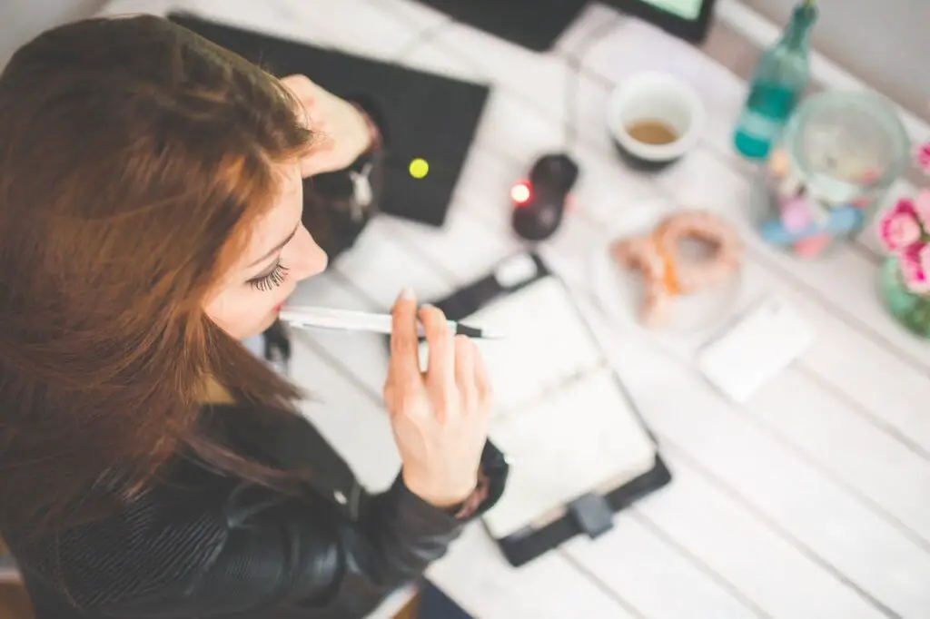 Woman thinking before writing on how to be successful at work