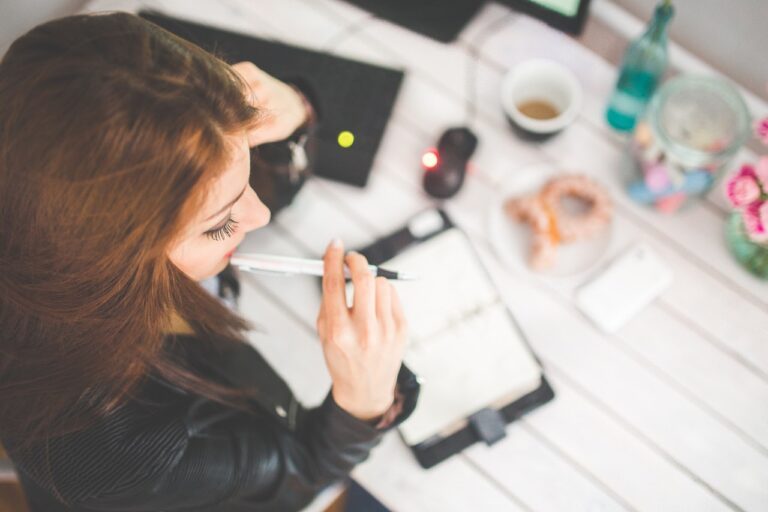 Woman thinking before writing on how to be successful at work