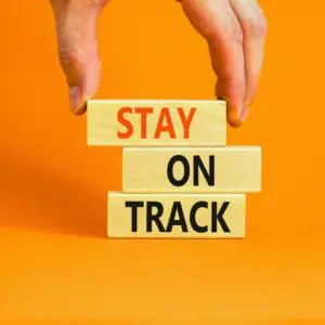 Image of a person placing three blocks with the words Stay on track.